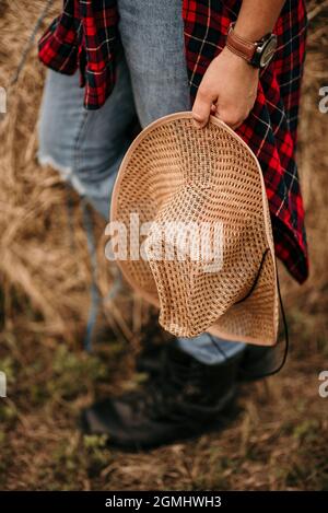 Ein junger Mann mit einem braunen Hut in der Hand, der auf einem Feld läuft Stockfoto