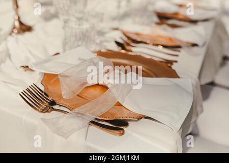 Wunderschöne goldene Teller auf dem Tisch am Hochzeitstag. Dekoration für Feiern, Hochzeiten und Geburtstage Stockfoto