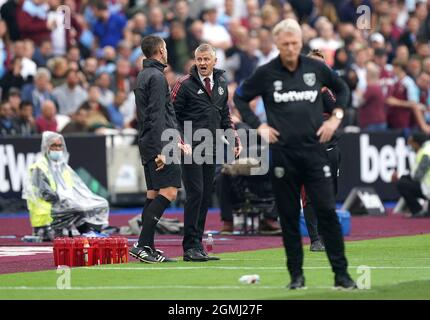 Manchester United Manager Ole Gunnar Solskjaer spricht mit dem vierten offiziellen David Coote (links), während West Ham United Manager David Moyes (rechts) während des Premier League Spiels im Londoner Stadion zuschaut. Bilddatum: Sonntag, 19. September 2021. Stockfoto