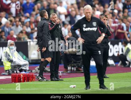 Manchester United Manager Ole Gunnar Solskjaer spricht mit dem vierten offiziellen David Coote (links), während West Ham United Manager David Moyes (rechts) während des Premier League Spiels im Londoner Stadion zuschaut. Bilddatum: Sonntag, 19. September 2021. Stockfoto