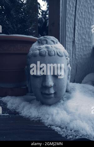 Stein buddha Kopf auf Holzterrasse mit Schnee bedeckt Stockfoto