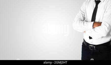 Mann, der auf der rechten Seite mit gefalteten Händen auf weißem isoliertem Hintergrund steht. Freier Platz mit einem Mann in weißem Hemd und schwarzem Stent Stockfoto