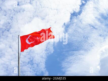 Türkische Flagge schwenkt an einem sonnigen Tag gegen den blauen Himmel Stockfoto