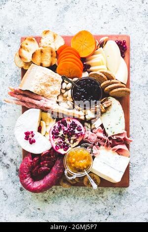 Charcuterie-Board. Käseplatte: Parmesan, Caciocavallo, Camembert und andere mit Prosciutto, Salami, Früchten und Nüssen. Auswahl an leckeren Vorspeisen Stockfoto