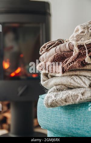 Ein Stapel warmer Kleidung auf einem Sessel, einem eisernen Kamin mit einem Stockfoto