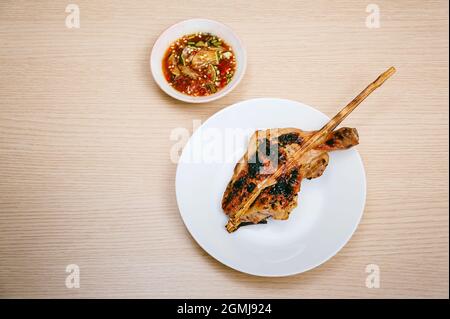 Isolate Gericht aus gegrilltem Hähnchenschenkel und Drumstick kommen mit thai-Stil würzige Chilisauce gemischt aus Fischsauce, rote Chili, Limette, in Scheiben geschnittenen Frühlingszwiebel etc Stockfoto