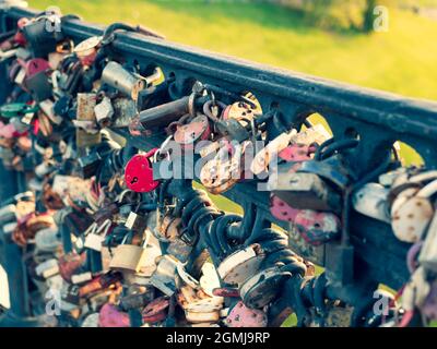 Vorhängeschloss in Form des Herzens neben anderen Vorhängeschlössern, die Paare als Simbol unsterbenser Liebe hängen. Liebe Vorhängeschlösser auf der Stadtbrücke. Hochzeitstradition Stockfoto