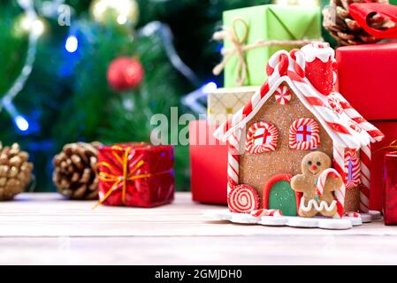 Weihnachtshaus aus Lebkuchengebäck in Weihnachtsstimmung mit einem Weihnachtsbaum im Hintergrund dekoriert. Lebkuchenhaus auf dem Stockfoto