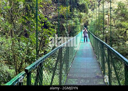 Mann, der Fotos von einer Hängebrücke aus gemacht hat. Nebelwald von Costa Rica. Stockfoto