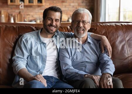 Familienportrait lächelnd reifer Vater und erwachsener Sohn umarmen sich Stockfoto