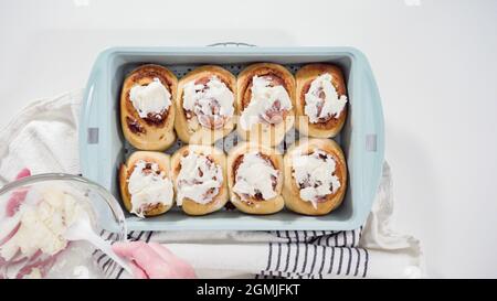 Flach liegend. Glasur frisch gebackene Zimtschnecken in einer blauen Backform. Stockfoto