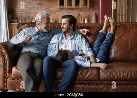 Glückliche drei Generationen von Männern, die sich gemeinsam auf der Couch entspannen Stockfoto