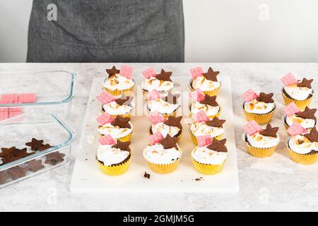 Gourmet-S'mores-Cupcakes mit Meringue-Zuckerguss und garniert mit sternförmiger Schokolade graham Cracker und einer pinken Mini-Tafel Schokolade. Stockfoto