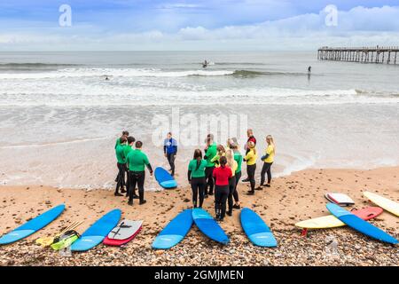 Surfboard-Schule mit Instruktor, Schülern und Surfbrettern am Strand von Saltburn by the Sea, Redcar und Cleveland District, North Yorkshire, England, Stockfoto