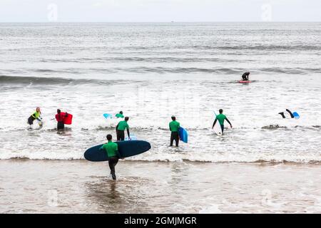 Serfers am Strand und in der Nordsee bei Saltburn by the Sea, North Yorkshire, England, Großbritannien Stockfoto