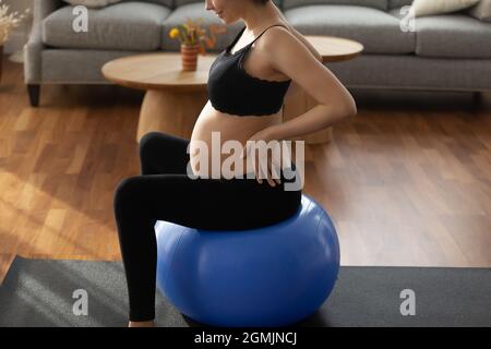 Zukünftige Mama in Sportbekleidung üben Gymnastik für Schwangere auf Fitball Stockfoto