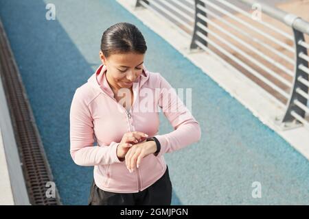 Junge sportliche Frau mit Fitness-Armband beim Joggen am Morgen im Freien Stockfoto