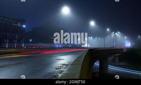 Dichter Nebel umgab Helsinki im Herbst 2021. Langzeitaufnahme von Straßen- und Autospuren. Kalasatama, Helsinki, Finnland. Stockfoto