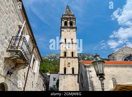 Der hohe, schmale und markante Glockenturm, der sich über charaktervollen alten Gebäuden erhebt, bei der Sommersonne. Stockfoto