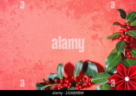 Weihnachtliche Stechpalme auf rotem Grunge-Hintergrund mit Kopierfläche Stockfoto