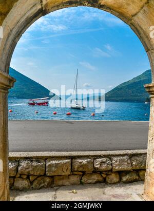 Ein Segelboot schwimmt in der Sommersonne auf dem ruhigen blauen Wasser der Bucht in der Nähe von Kotor. Stockfoto