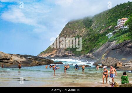 Touristen genießen den Strand von Itacoatiara in Niteroi, Rio de Janeiro, Brasilien. Mit einer wunderschönen Landschaft ist dieser Strand berühmt für das ideale CO Stockfoto