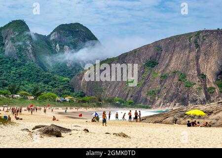 Touristen genießen den Strand von Itacoatiara in Niteroi, Rio de Janeiro, Brasilien. Mit einer wunderschönen Landschaft ist dieser Strand berühmt für das ideale CO Stockfoto