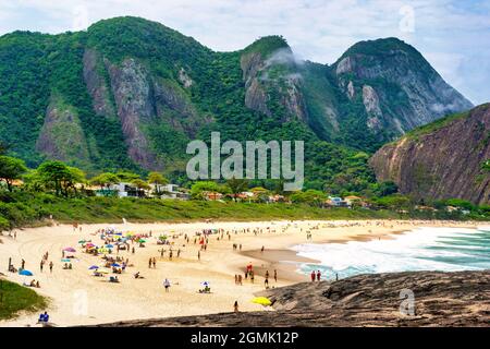 Touristen genießen den Strand von Itacoatiara in Niteroi, Rio de Janeiro, Brasilien. Mit einer wunderschönen Landschaft ist dieser Strand berühmt für das ideale CO Stockfoto