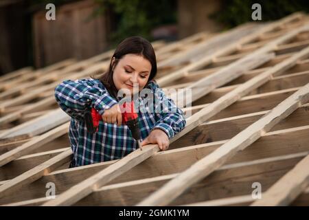 Die junge Arbeiterin macht den Rahmen des Daches Stockfoto