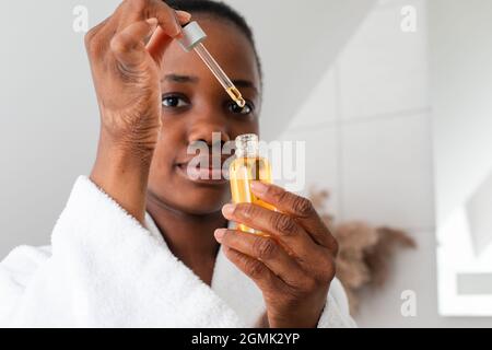 Flasche Serum mit Tropfen, der von der Pipette fällt Stockfoto