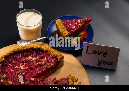 Obst Käsekuchen und ein Glas Milch für die Liebsten zubereitet, am Valentinstag auf schwarzem Hintergrund. Stockfoto