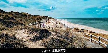Eine malerische Küste mit einer Holzpromenade unter einem blau bewölkten Himmel Stockfoto