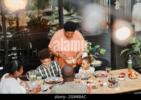Porträt einer älteren afroamerikanischen Oma, die beim Familienessen im Freien Essen serviert, Kopierbereich Stockfoto
