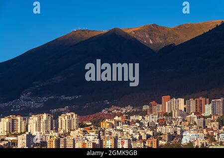 Skyline von Quito bei Sonnenaufgang mit modernem Hochhaus-Apartmentgebäude mit dem Vulkan Pichincha, Ecuador. Stockfoto