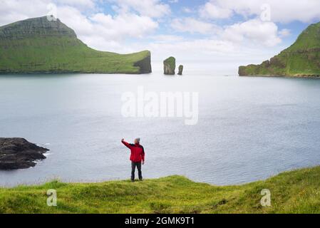 Der Reisende macht ein Selfie auf dem Hintergrund der Drangarnir-Seestacks und der Tindholmur-Insel auf den Färöer-Inseln Stockfoto