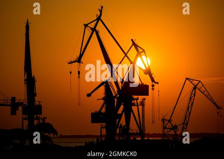 Silhouetten von Kränen bei Sonnenuntergang an den Docks und Hafen von Pula, Istrien, Kroatien Stockfoto