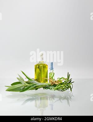 Zwei Arten von Kräuterextrakt in Glasflaschen mit Pipettendispensern. Öl und Wasser Alkohol Salbei und Rosmarin. Stockfoto