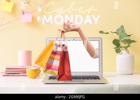 Frau hielt sich mit Einkaufstaschen aus dem Laptop-Bildschirm auf den Tisch im Büro. Cyber Monday Sale Stockfoto