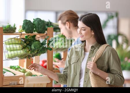 Junge Frau, die Gemüse auf dem Markt wählt Stockfoto