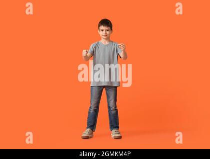 Kleiner Junge mit imaginärem Lenkrad auf farbigem Hintergrund Stockfoto