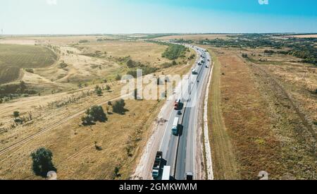 Logistik Frachttransport Konzept. Viele Fracht-Lkw fahren auf der Autobahn zwischen Autos, Luftbild. Stockfoto