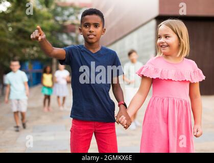 Präteen Mädchen zu Fuß mit afroamerikanischen Freund entlang der Stadt Straße Stockfoto