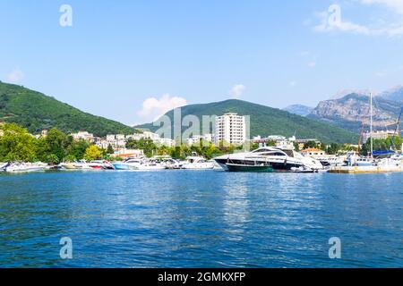 Nahaufnahme der Stadt Budva von einer Yacht aus, im Hintergrund eine Bergkette mit Vegetation. Reisen Sie entlang der Küste Montenegros. Stockfoto