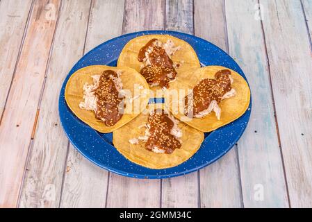 Tablett mit vier mexikanischen Chicken Tacos mit Maulwurf, Sesamsamen und Mais-Tortillas Stockfoto