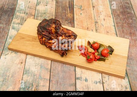 Den ganzen Sonntag gebratenes Hähnchen mit der gut gebratenen Haut, garniert mit Kirschtomaten, Paprika und gebratenen Pilzen auf Holzbrett Stockfoto