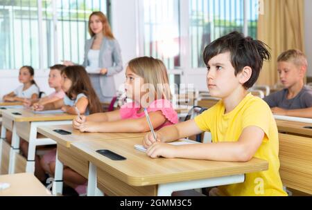 Fleißiger Jugendlicher, der mit Klassenkameraden in der Schule studiert Stockfoto