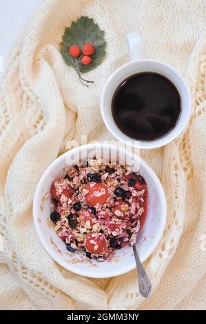 Ein Teller Haferflocken mit Beeren und einer Tasse Kaffee Stockfoto