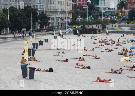 Coruna-Spanien. Blick auf den Strand von Riazor in La Coruña mit Badegästen und mehreren Behältern zum Recycling von Dosen und Müll am 12. September 2021 Stockfoto