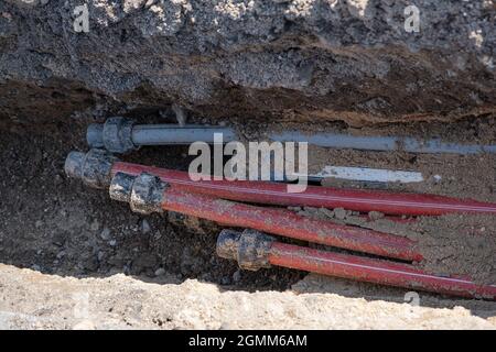 Auf der Straße sind neue Kommunikations-Infrastrukturen für warmes und kaltes Wasser unterirdisch vergraben. Wasserversorgung Baustelle mit vielen Rohrleitungsrohren. Stockfoto