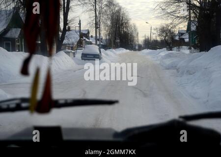 Wjasnyky, Russland. 5. Februar 2017. Blick auf die Stadt vom Auto aus. Straße mit ein- und zweistöckigen Häusern Stockfoto